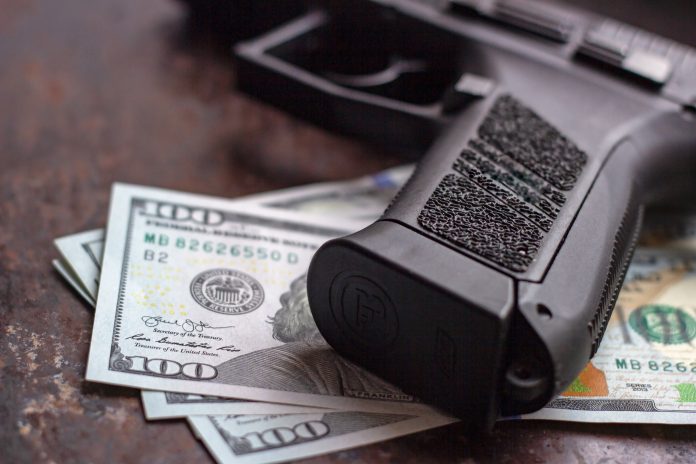 Black,Gun,On,American,Dollars,Background.,Military,Industry,,War,,Global
