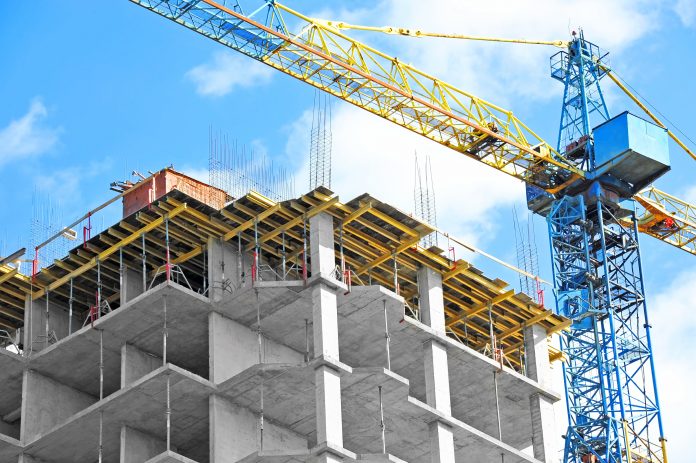 Crane,And,Building,Under,Construction,Against,Blue,Sky