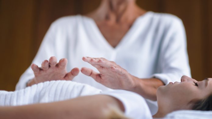 Professional,Reiki,Healer,Doing,Reiki,Treatment,To,Young,Woman,In